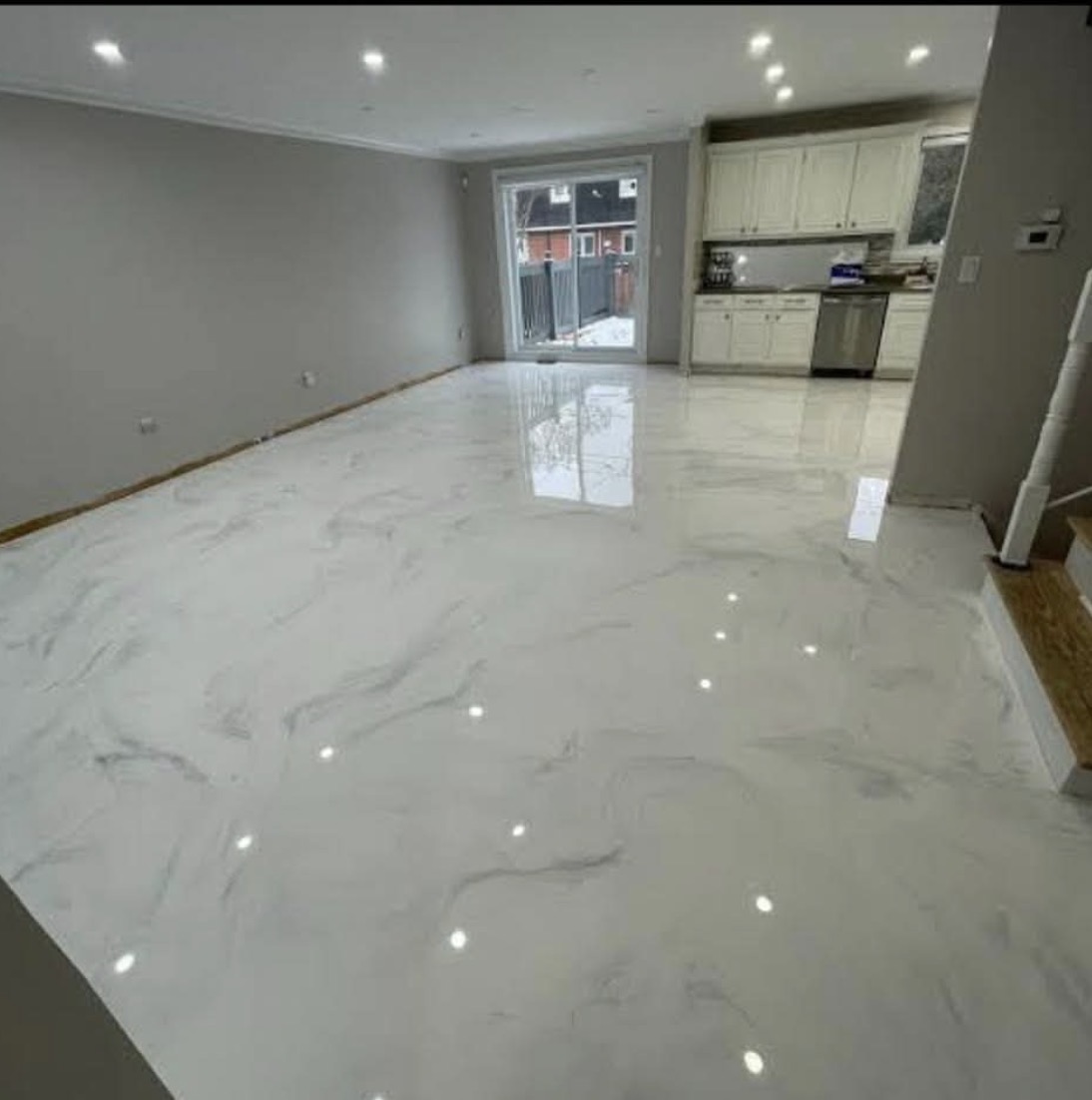 Salon et cuisine ouverts avec plancher époxy métallique effet marbre blanc veiné de gris