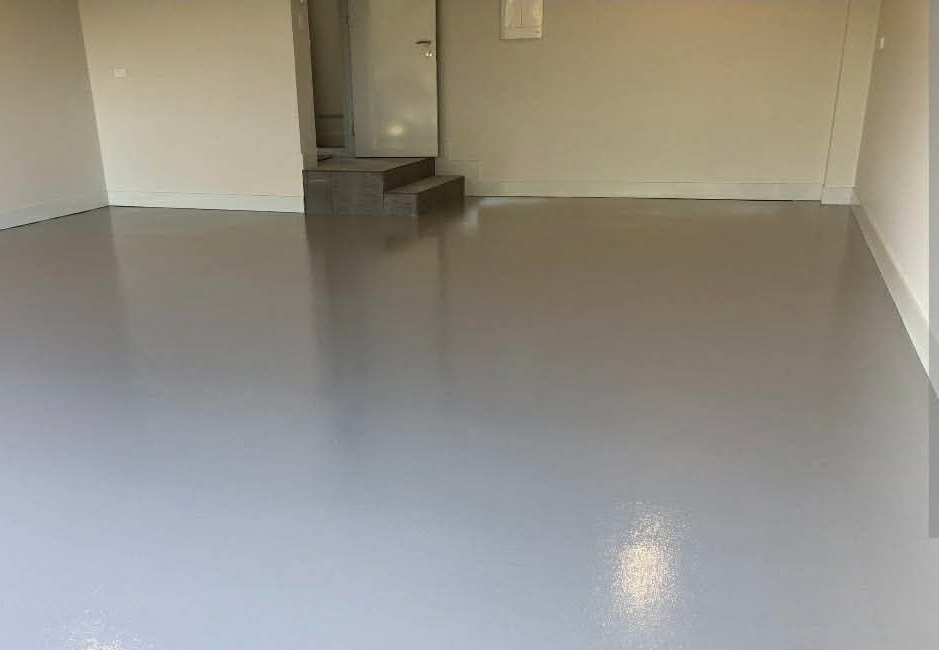 Sous-sol fini avec plancher époxy uni gris clair au fini brillant, escalier et plinthes blanches