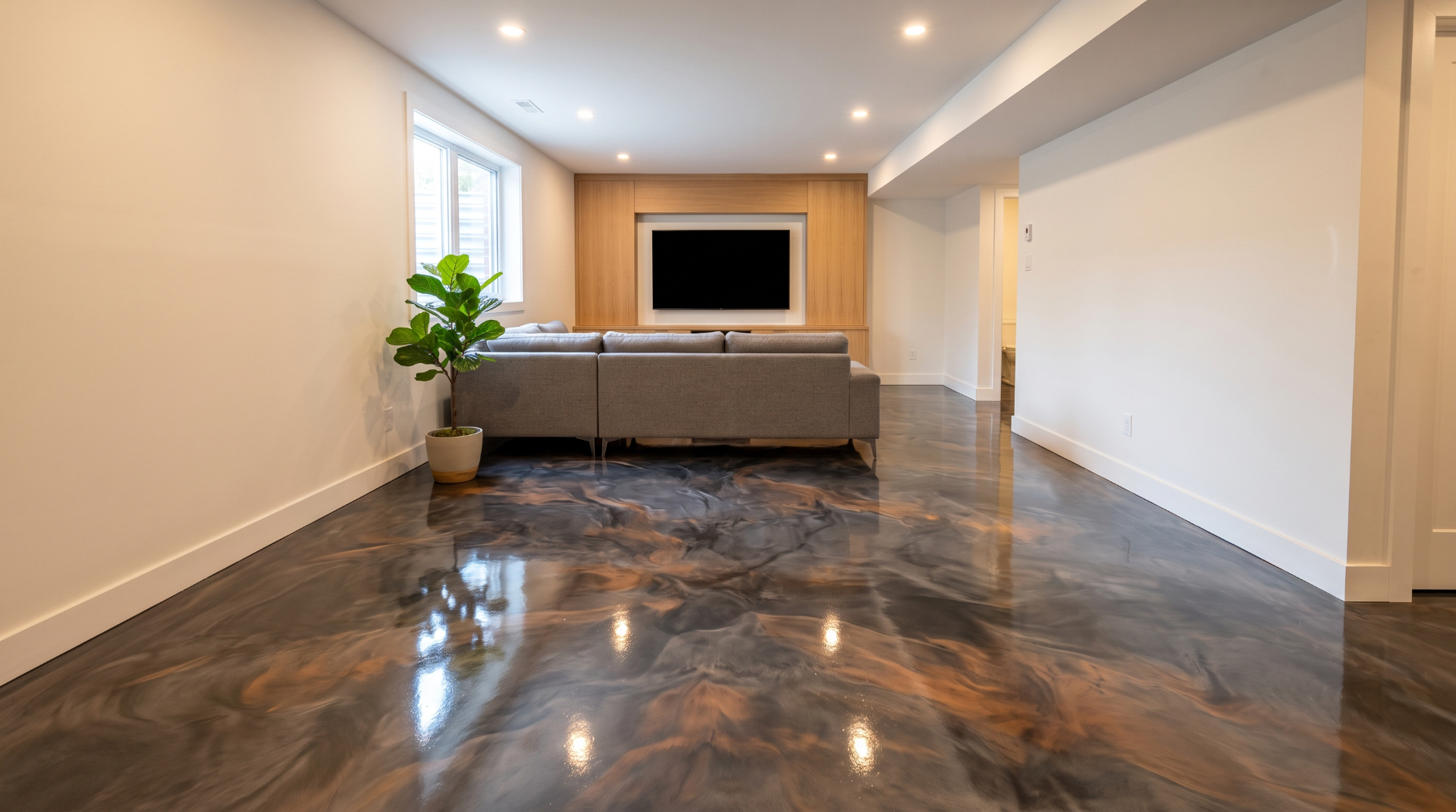 Salle familiale de sous-sol avec plancher époxy métallique anthracite et marbrures bronze